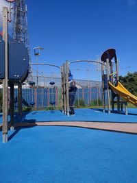 Rear view of men at playground against clear blue sky