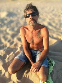 Man wearing sunglasses sitting on beach