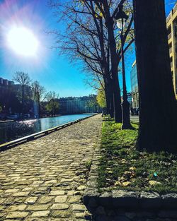 Footpath by canal against sky