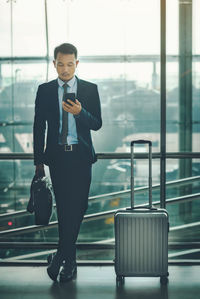 Full length of man using mobile phone in bus