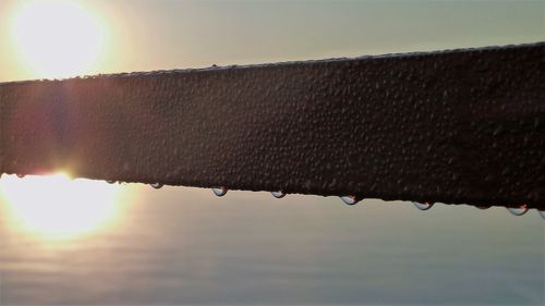 Close-up of water drops on rusty metal against sky