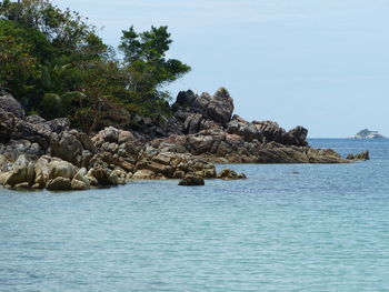 Scenic view of rocks by sea against sky