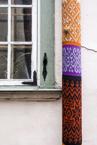 Rolled colorful fabric by closed window of building