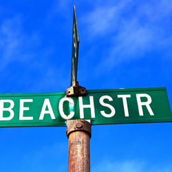 Low angle view of road sign against blue sky