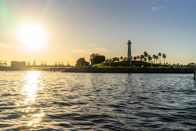 River by factory against sky during sunset