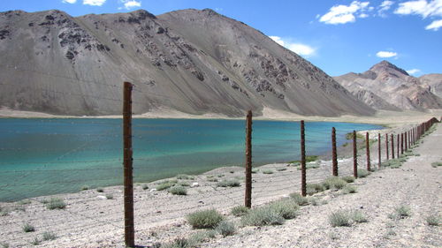 Fence by lake against mountains