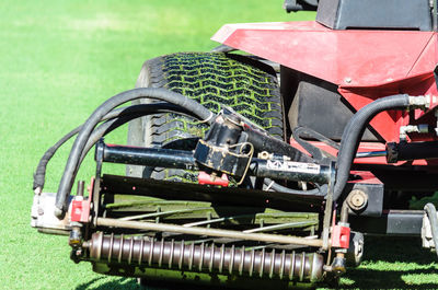 A big wheel of grass tractor on the football field.