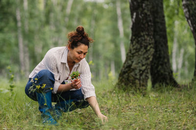 Woman picking wild strawberry in forest on summer day outdoor natural scene