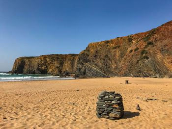 View of rocks on beach against clear sky