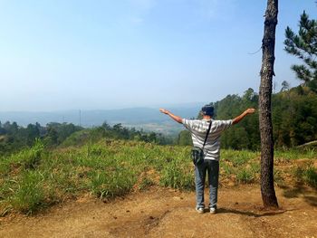 Rear view of man with arms outstretched standing on mountain