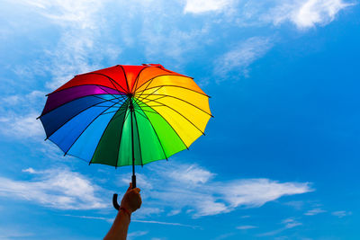 Low angle view of person holding umbrella against sky