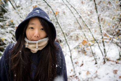 Portrait of woman wearing hood while standing in snow