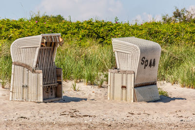 Hooded beach chairs by grass on sunny day