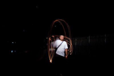 Rear view of woman standing against illuminated lights at night