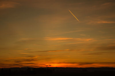 Silhouette landscape against orange sky