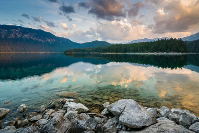 Lake by mountains against sky during sunset