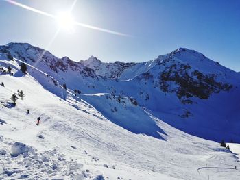 Scenic view of snowcapped mountains against blue sky during sunny day