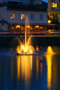 Illuminated bridge over river in city at night