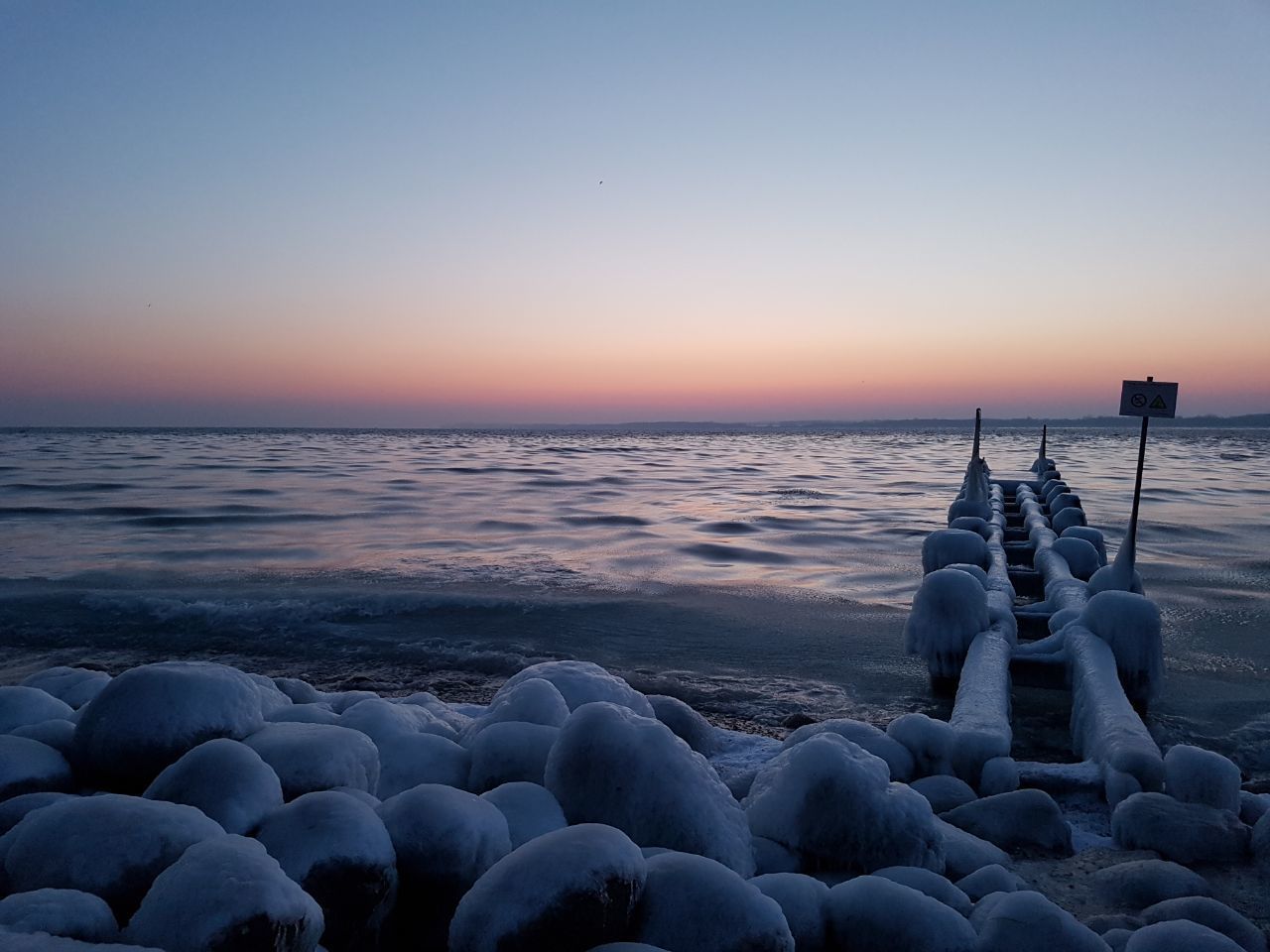 sunset, beauty in nature, tranquil scene, sea, beach, nature, water, outdoors, pebble, no people, scenics, cold temperature, tranquility, sky, horizon over water, pebble beach, day, close-up