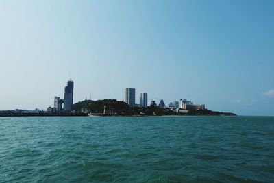 Sea by buildings against clear sky