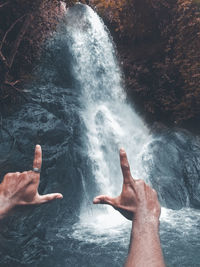 Midsection of people in water at waterfall