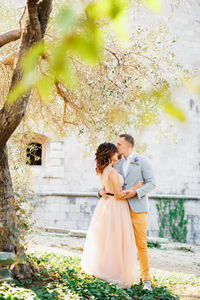 Young couple standing against tree