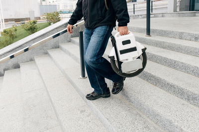 Man carrying electric unicycle on city street. mobile portable individual transportation vehicle