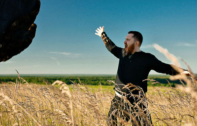 Hunter screaming while standing on grassy field against sky