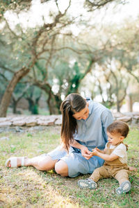 Rear view of mother and daughter sitting on tree