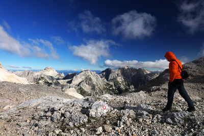 Side view of man hiking on rocks against sky