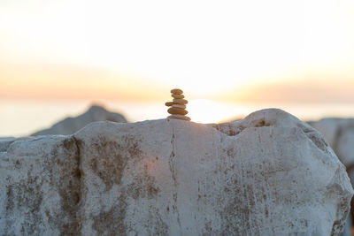 Close-up of rock by sea against sky during sunset