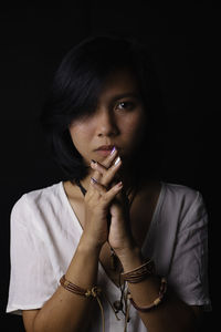 Portrait of beautiful young woman against black background