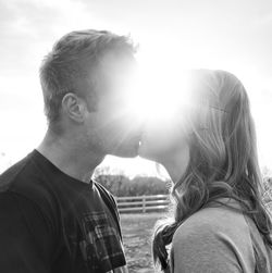 Couple kissing against bright sky