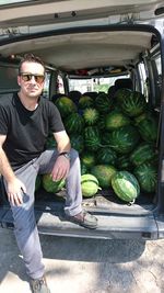 Man standing by pick-up truck with watermelons