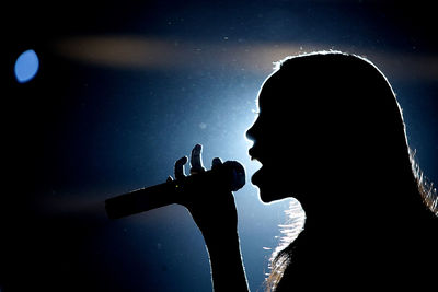 Low angle view of silhouette woman standing against sky at night