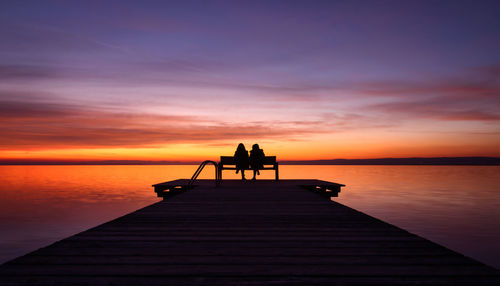 Silhouette people on pier over sea against sky during sunset