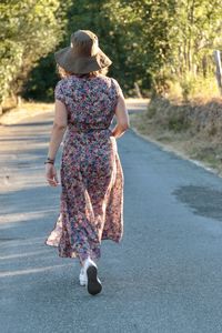 Rear view of woman walking on road in country 