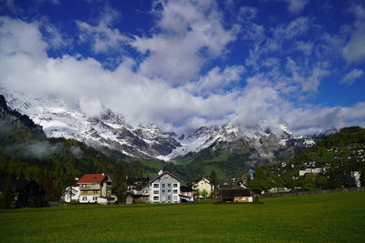 Scenic view of field and houses against sky