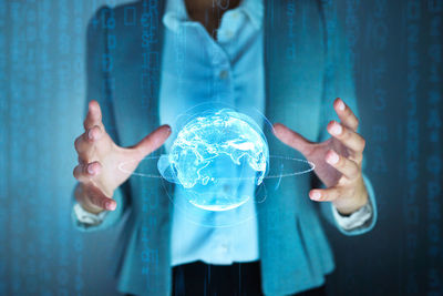 Midsection of woman with arms raised standing against wall