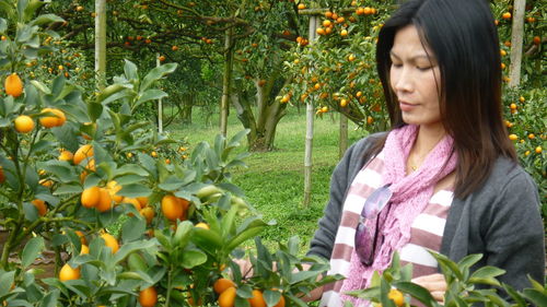 Mature woman standing by oranges on tree