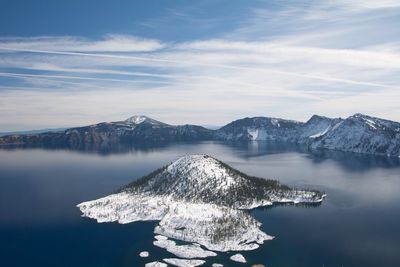 Scenic view of lake by snowcapped mountains against sky