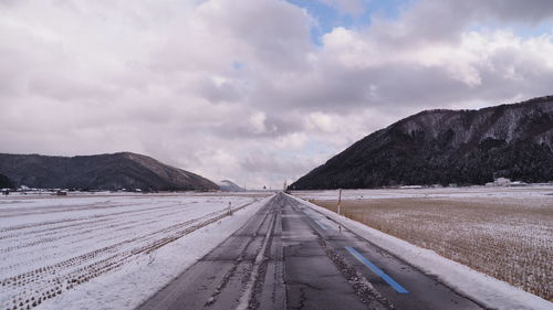 Road leading towards mountains against sky