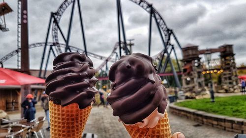 People in amusement park against sky in city