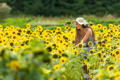 Close-up of woman with yellow flowers on field