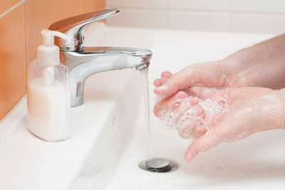 Midsection of woman cleaning hands in bathroom at home