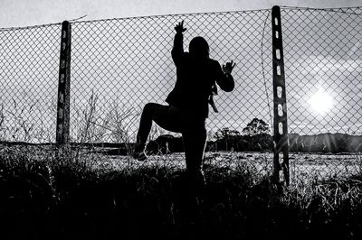 Silhouette men playing soccer on field against sky