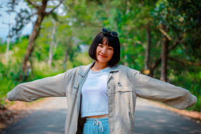 Portrait of young woman standing against trees