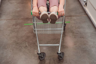 The girl's legs stick out of the basket in the shopping hall of the supermarket. riding in a cart