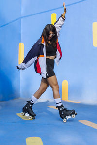 Woman wearing roller skates dancing by wall