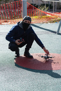 Full length portrait of man flying drone outdoors